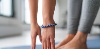 Yoga at home exercise in living room house - woman on fitness mat training stretching legs touching toes.